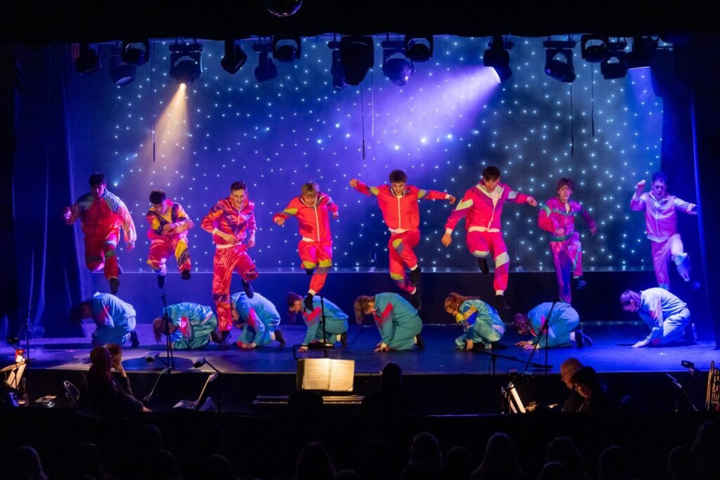 Harpenden Gang Show dancers in shell suits leaping