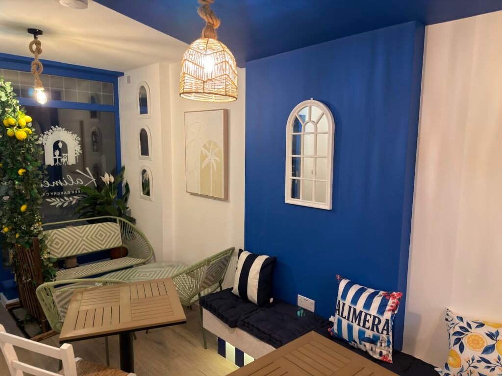 Blue-walled seating area with cushioned benches at Kalimera, Harpenden